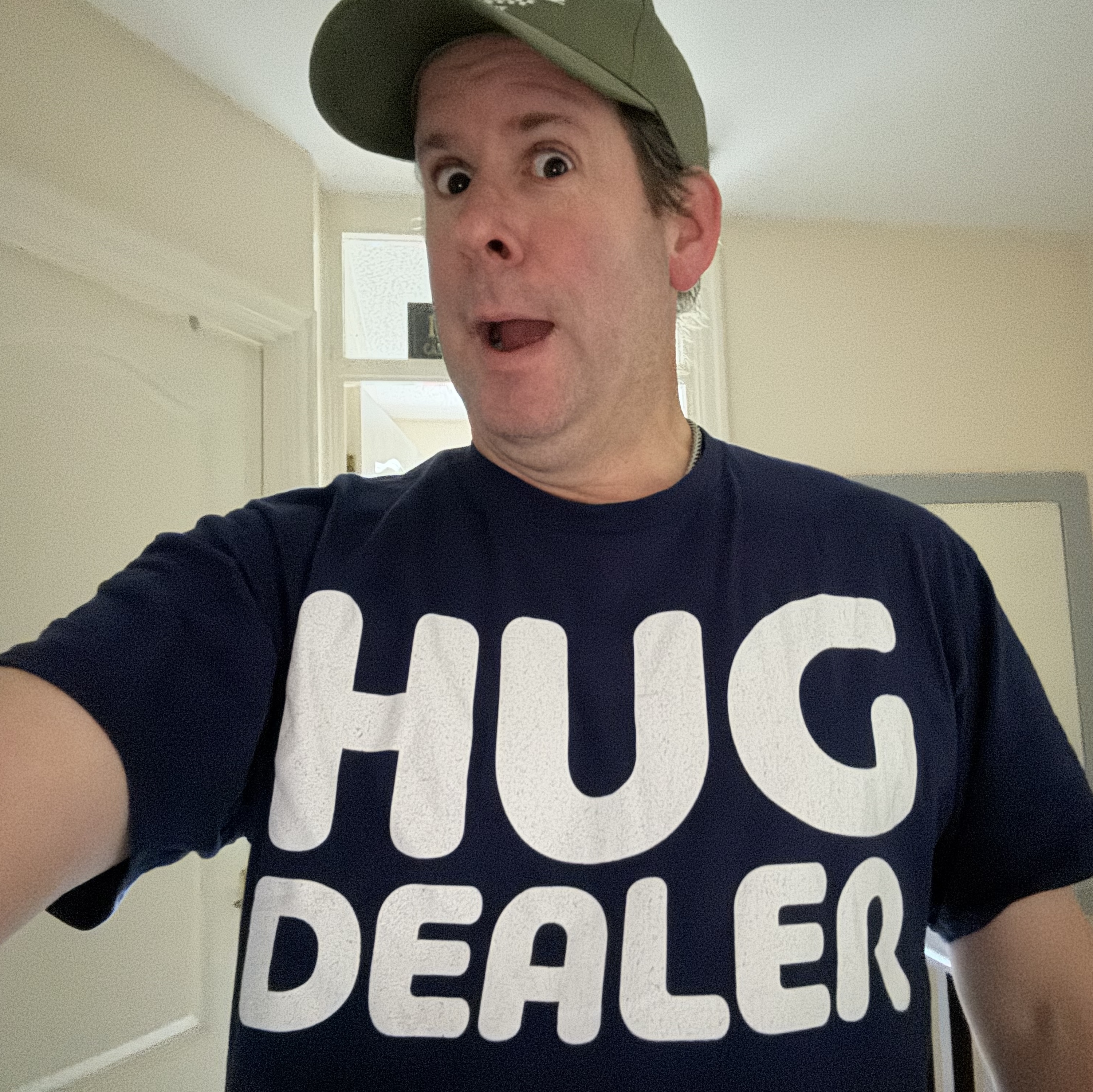 Ian Lloyd pulling a silly face (or is that his normakl face?), wearing a T Shirt that says 'Hug Dealer'